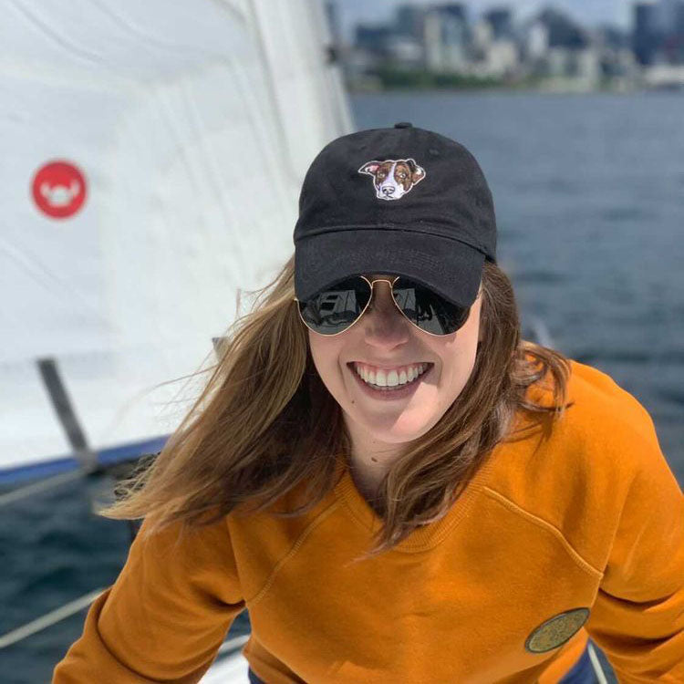 Young woman wearing a black dog dad hat on a boat.