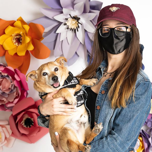 Dog mom wearing a custom maroon dog dad hat while holding her dog.